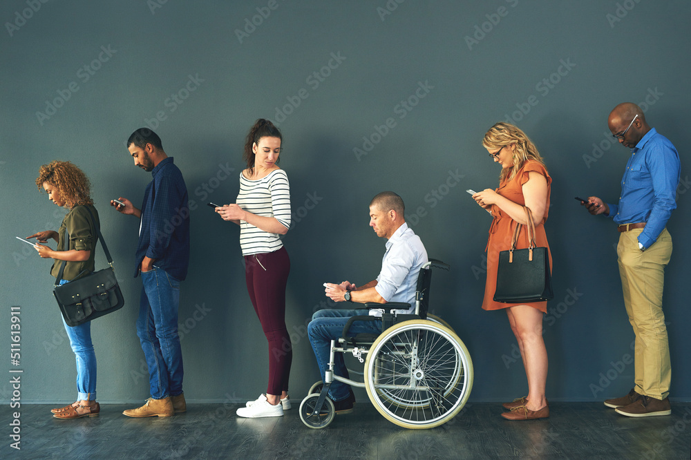 Poster We all have the same phone. Shot of a group of people standing in a row behind each other while using their phones.