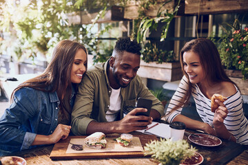 Want to see something funny. Shot of three friends looking at something on a cellphone while out...