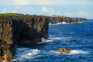 Cliffs of lava rock plummeting into the Pacific Ocean on the southern side of the Hawaiian Volcanoes National Park on the Big Island of Hawai'i, near the Holei Sea Arch along the Chain of Craters Road