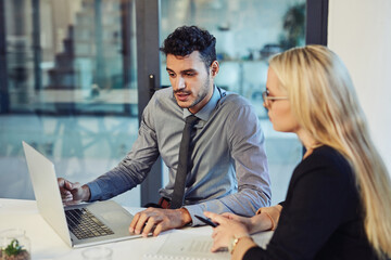 Transforming productivity with teamwork. Shot of a young businessman and businesswoman using a laptop together during a meeting in a modern office.