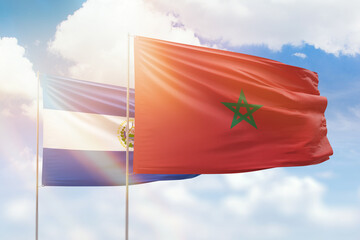 Sunny blue sky and flags of morocco and el salvador