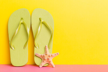 Beach accessories. Flip flops and starfish on colored background. Mock up with copy space