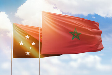 Sunny blue sky and flags of morocco and papua new guinea
