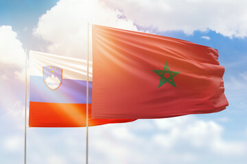 Sunny blue sky and flags of morocco and slovenia