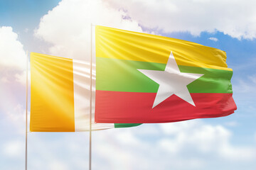 Sunny blue sky and flags of myanmar and ivory coast