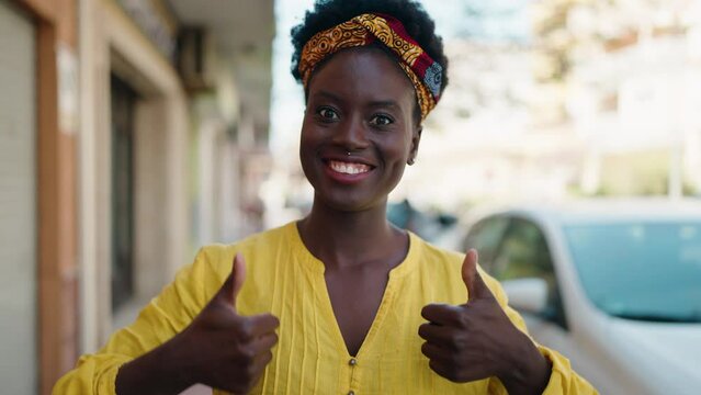 Young african american woman smiling confident doing ok sign with thumbs up at street