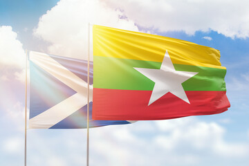 Sunny blue sky and flags of myanmar and scotland