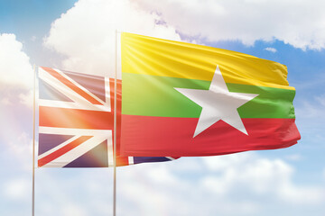 Sunny blue sky and flags of myanmar and united kingdom
