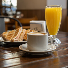 an orange juice with toasted ham and cheese and a coffee with milk