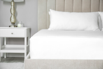 Mattress with white fitted sheet and pillows indoors