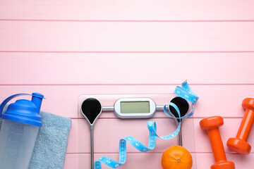 Flat lay composition with bathroom scale and measuring tape on pink wooden floor , space for text. Weight loss concept