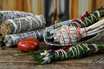 A close up image of various healing smudge sticks with abalone shell and healing crystals. 
