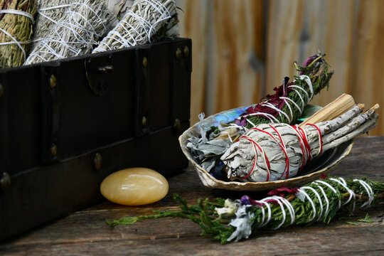A close up image of various healing smudge sticks with abalone shell and healing crystals. 