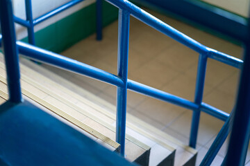Close-up at stairway with blue metal handrail. Building interior part photo, selective focus.