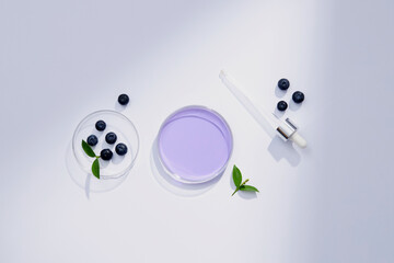 Top view of blueberry extract with transparent podium and cosmetic jar in white background 