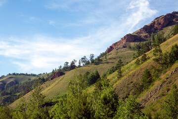 Obraz premium Summer landscape, mountains and rocks against a blue sky with clouds, with copy space. Tourism, active recreation.