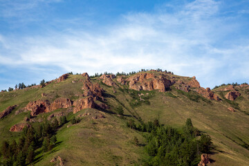 Summer landscape, mountains and rocks against a blue sky with clouds, with copy space. Tourism, active recreation.