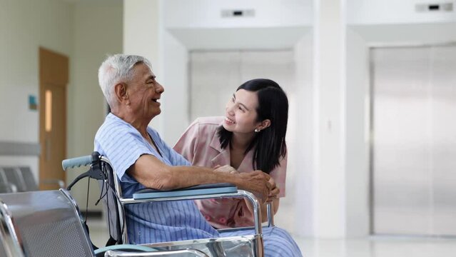 Asian elder male patient sitting on wheelchair. Woman doctor talk with senior patient at ceception medical hospital.