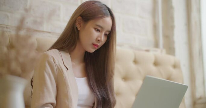 Young beautiful asian female businesswoman freelance using laptop computer remote work in coworking space cafe. Attractive talent woman university girl watching distance online learning seminar class.