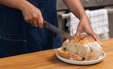 Woman Cutting freshly baked sourdough bread.