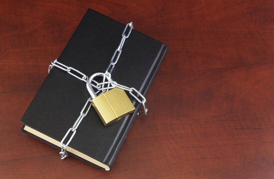 Banned Information And Censorship Concept, Black Book With Chain And Padlock On Wooden Table. Copy Space For Text