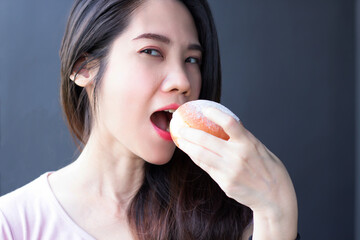 Asian beautiful woman are eating  doughnut bun with smiling and happiness during coffee break or breakfast