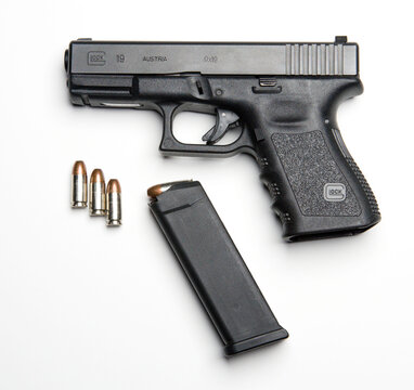 A Glock 19 handgun with magazine and ammunition on a white background