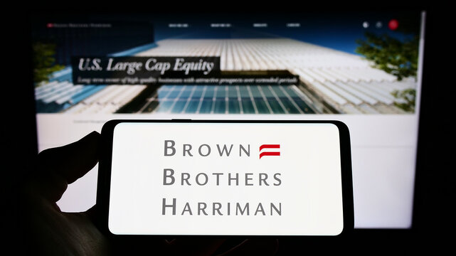 Stuttgart, Germany - 06-12-2022: Person holding cellphone with logo of American company Brown Brothers Harriman Co. (BBH) on screen in front of webpage. Focus on phone display.