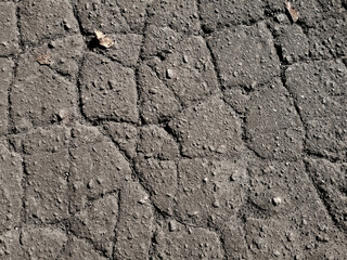 Cracked asphalt texture close-up, top view. Gray abstract grunge pattern
