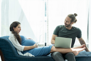 Happy husband and pregnant wife spending time together at home. Pregnancy, family and people.