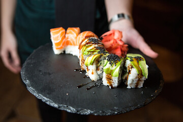 Philadelphia sushi roll with salmon, cucumber, avocado, cream cheese. Sushi menu. Japanese food. On a plate. On dark background.