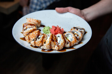 Philadelphia sushi roll with salmon, cucumber, avocado, cream cheese. Sushi menu. Japanese food. On a plate. On dark background.