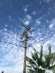 Electricity pole and power line under white cloud and blue sky