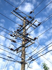 Electricity pole and power line under white cloud and blue sky