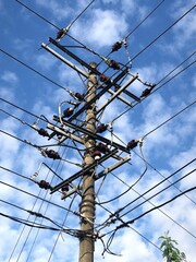 Electricity pole and power line under white cloud and blue sky