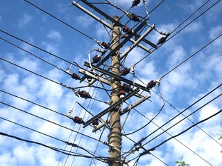 Electricity pole and power line under white cloud and blue sky
