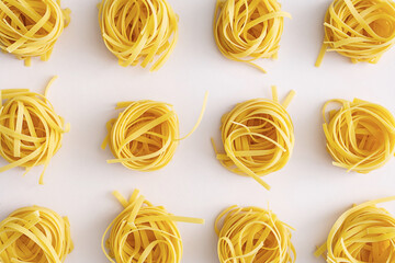 Homemade raw twisted pasta on pink table. Mediterranean food background.