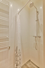 Shower faucets attached to tiled wall near glass partition and ornamental curtail in washroom at...