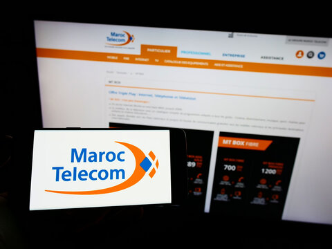 Stuttgart, Germany - 02-13-2022: Person holding cellphone with logo of telecommunications company Maroc Telecom (IAM) on screen in front of webpage. Focus on phone display.