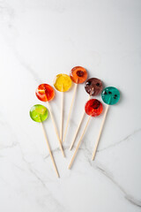 Fototapeta na wymiar Top view of mealting homemade fruits candy lollipop on light surface