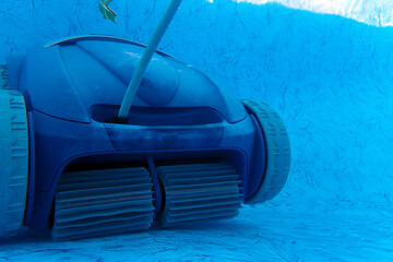 Underwater closeup of a motorized pool vacuum cleaner with wheels and beaters.