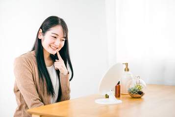 部屋で鏡を見る肌荒れが治った女性（笑顔・口）
