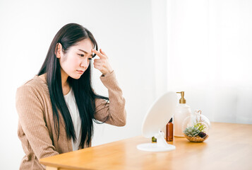 鏡の前で肌に悩む女性（おでこ・眉間）
