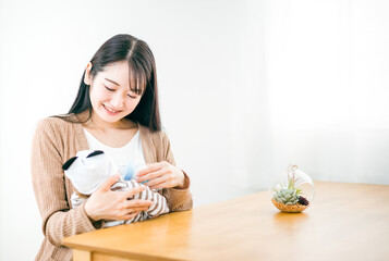 赤ちゃんに哺乳瓶でミルクを飲ませる女性（笑顔）
