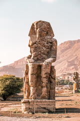 
Ancient Egyptian Colossi of Memnon stone pharaoh statue with mountain background at Valley of the Kings in Luxor