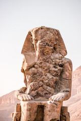 Ancient Egyptian Colossi of Memnon stone pharaoh statue with mountain background at Valley of the...