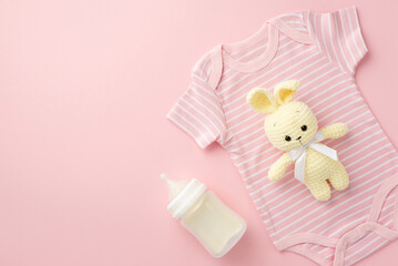 Baby accessories concept. Top view photo of pink bodysuit knitted bunny toy and bottle on isolated pastel pink background with copyspace