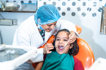 smiling Dentist treating toothache of kid at hospital - concept of dental care, expertise and...