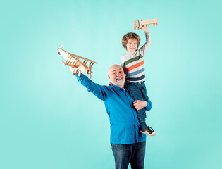Child boy and grandfather piggyback with toy plane and wooden truck. Men generation granddad and grandchild.