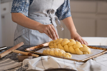 The girl makes challah bread in the kitchen and smears butter with a brush.